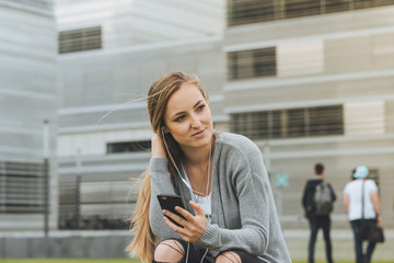 young beautiful girl with long hair  hearing a music with smart phone outdoor