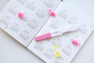 pregnant woman with pregnancy test watching calendar and calculating bith date