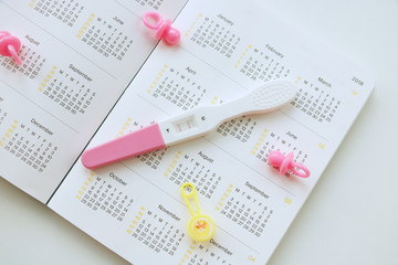 pregnant woman with pregnancy test watching calendar and calculating bith date