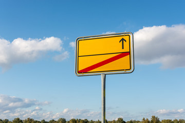 Blank yellow city sign with arrow and red struck through line in the street