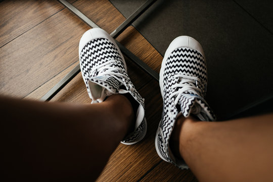 top view. foot of young asia woman wearing striped shoes with wood floor are background. image for sport,equipment,accessory,person concept
