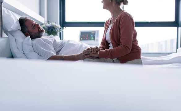 Woman visiting husband in hospital ward