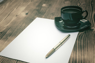 Empty Letter page, fountain pen and cup of coffee on the burnt table background. Writter desk table.