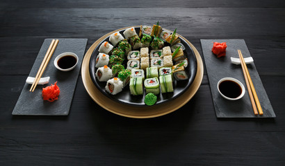 Set of sushi maki and rolls on black rustic wood
