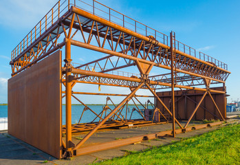 Rusty industrial steel construction on a quay below a blue sky