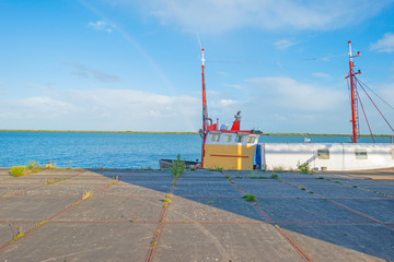Boat moored along a quay in sunlight in summer
