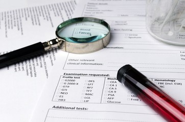 magnifying glass, beaker, blood sample test tube and patient information form on desk, heart healthcare technology, medical diagnosis, blood test, medical report record and history patient concept
