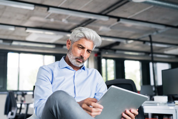 Mature businessman with tablet in the office.