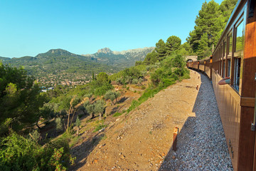Fototapeta na wymiar Soller wooden train driving through the Serra de Tramuntana mountains range and entering in a tunnel
