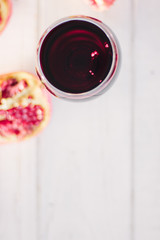 Organic pomegranate wine on white wooden table.