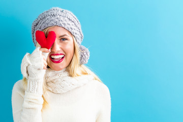 Happy young woman holding a heart cushion on a blue background