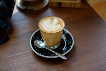 Cup of hot milk coffee with swan latte art on wooden table background. Concept of morning drink freshness. Selective focus