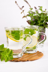 Two glass cups fresh mint tea with lemon and a bunch of mint in vase