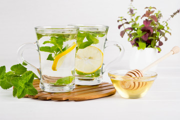 Two glass cups fresh mint tea with lemon and a bunch of mint in vase