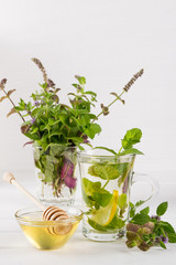 Two glass cups fresh mint tea with lemon and a bunch of mint in vase