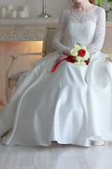 Obraz na płótnie Canvas Bride in white wedding dress sitting and holding wedding bouquet