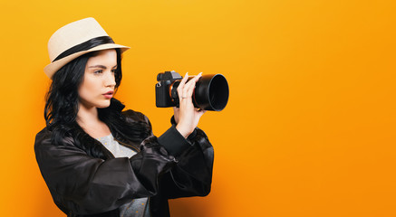 Young woman holding a camera on a yellow background
