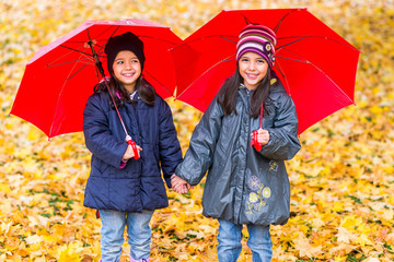Happy little girls laughing with  umbrellas in the rain