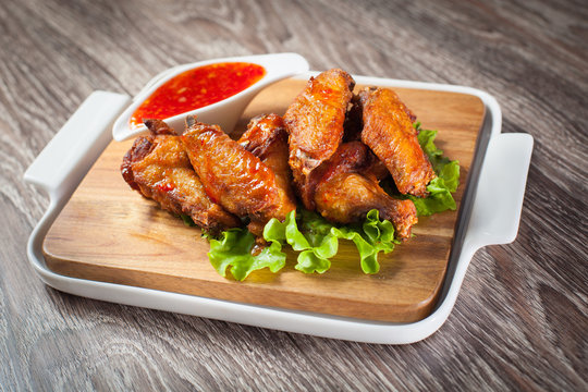 Wings of a grill on a wooden board with lettuce and barbecue sauce