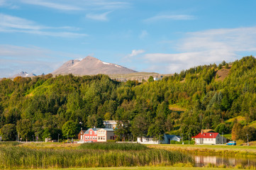 Buildings in old part of Akureyri city in Iceland with mountain Sulur in the background
