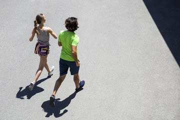 Handsome man and beautiful woman jogging together on street