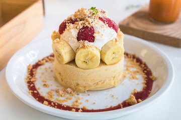 Hot cake with cream, strawberry, banana and cookie crumble on white dish