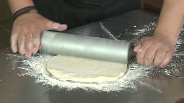 Baker hands kneading dough in flour on table Chef Tossing Pizza Dough. Skillful chef preparing a pizza