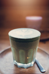 Matcha green tea latte art on wooden table.