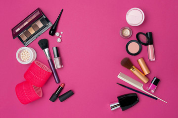 Various cosmetic products on a pink background.