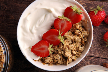 Healthy breakfast concept with oat flakes and fresh berries on rustic background. Food made of granola and musli. Healthy muesli with strawberries, nuts and milk.