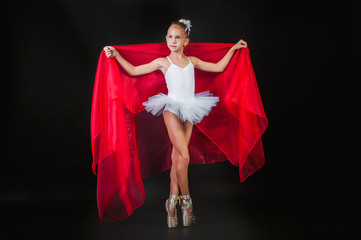 Little young ballerina posing with red cloth in hands on a black background. © kwadrat7