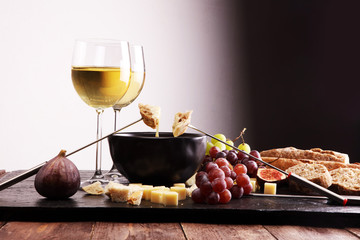 Gourmet Swiss fondue dinner on a winter evening with assorted cheeses on a board alongside a heated...