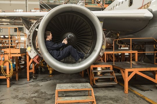 Male aircraft maintenance engineer fixing turbine blade of
