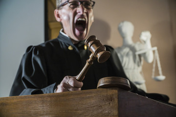 angry man a judge with a hammer in his hand in the court room
