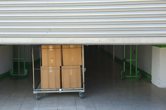 Entrance Into Self Storage Units, Big Cart With Carton Boxes In Front, Metal Gate