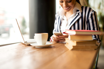 Stylish young girl is texting on mobile while having a break.