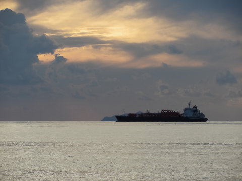 Warm sea sunset with cargo ship at the horizon . Giants cumulonimbus clouds are in the sky. Tuscany, Italy