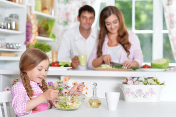 Obraz na płótnie Canvas Cute little daughter preparing salad