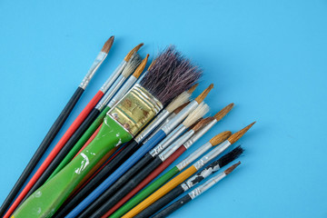 Row of artist paint brushes close up on blue  background