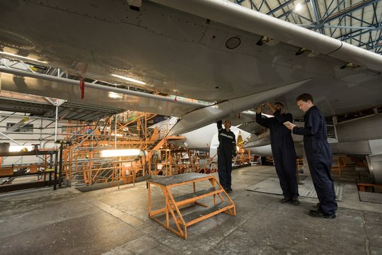 Aircraft maintenance engineers examining aircraft wing