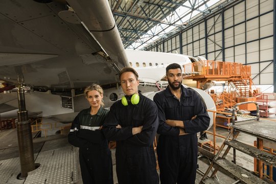 Aircraft maintenance engineers standing with arms crossed at