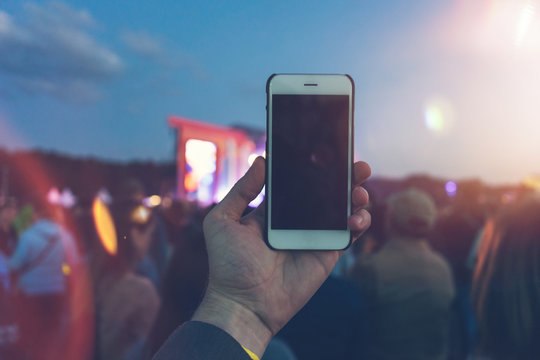 man taking pictures with smartphone on festival with blurry lens flares