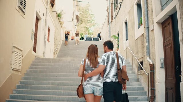 Young couple walking upstairs Mediterranean town street on vacation