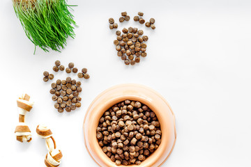 bowl full and overflowing with dry pet - dog food bits and paw prints on white background top view mock-up