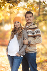 Fototapeta premium Young happy family have fun and walking in the autumn park. Pregnant woman with husband 