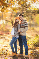 Young happy family have fun and walking in the autumn park. Pregnant woman with husband 