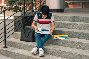 fashion guy reads books sitting on the street