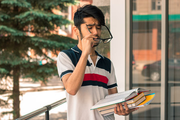cute guy stands on a street holding a book and dress glasses