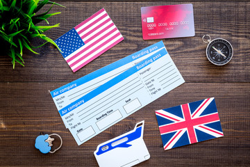 booking trip with tickets, flags and tourist outfit on wooden office desk background top view