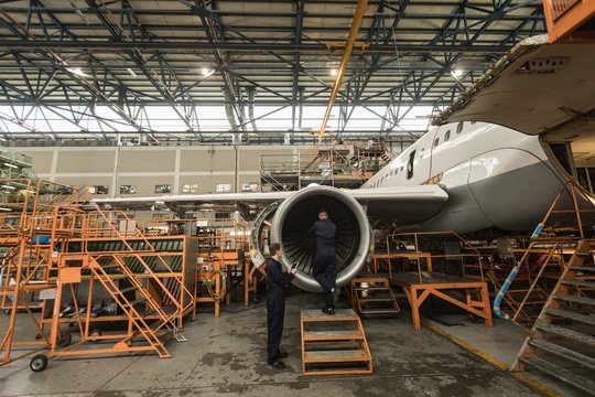 Aircraft maintenance engineers examining turbine engine of